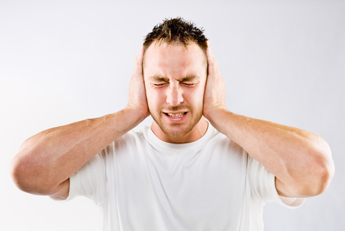 Man blocking out loud noise from ears.